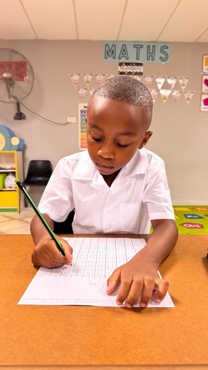 A young learner writing numbers in a maths lesson
