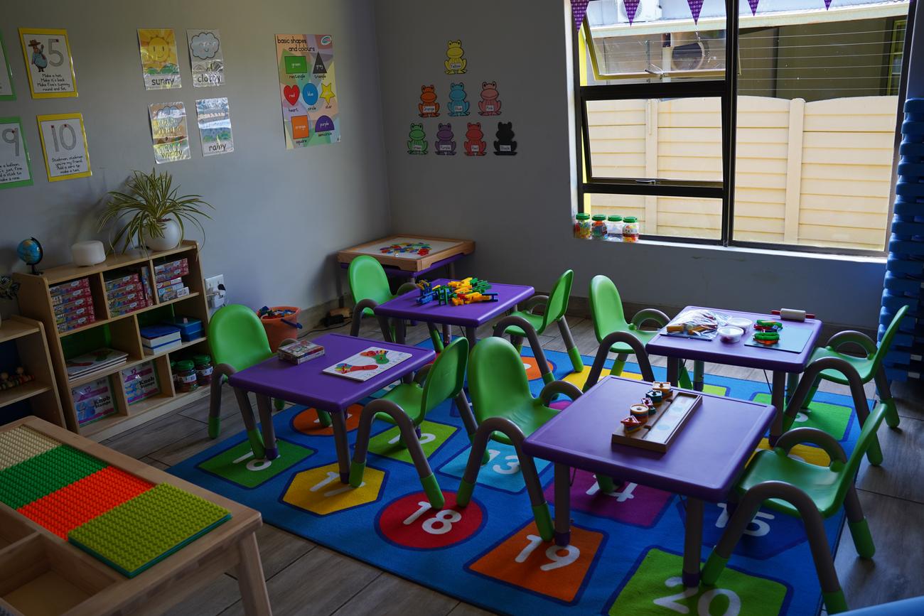 A Hibiscus classroom on Rivier Street with activities set out on purple tables over a numbers rug