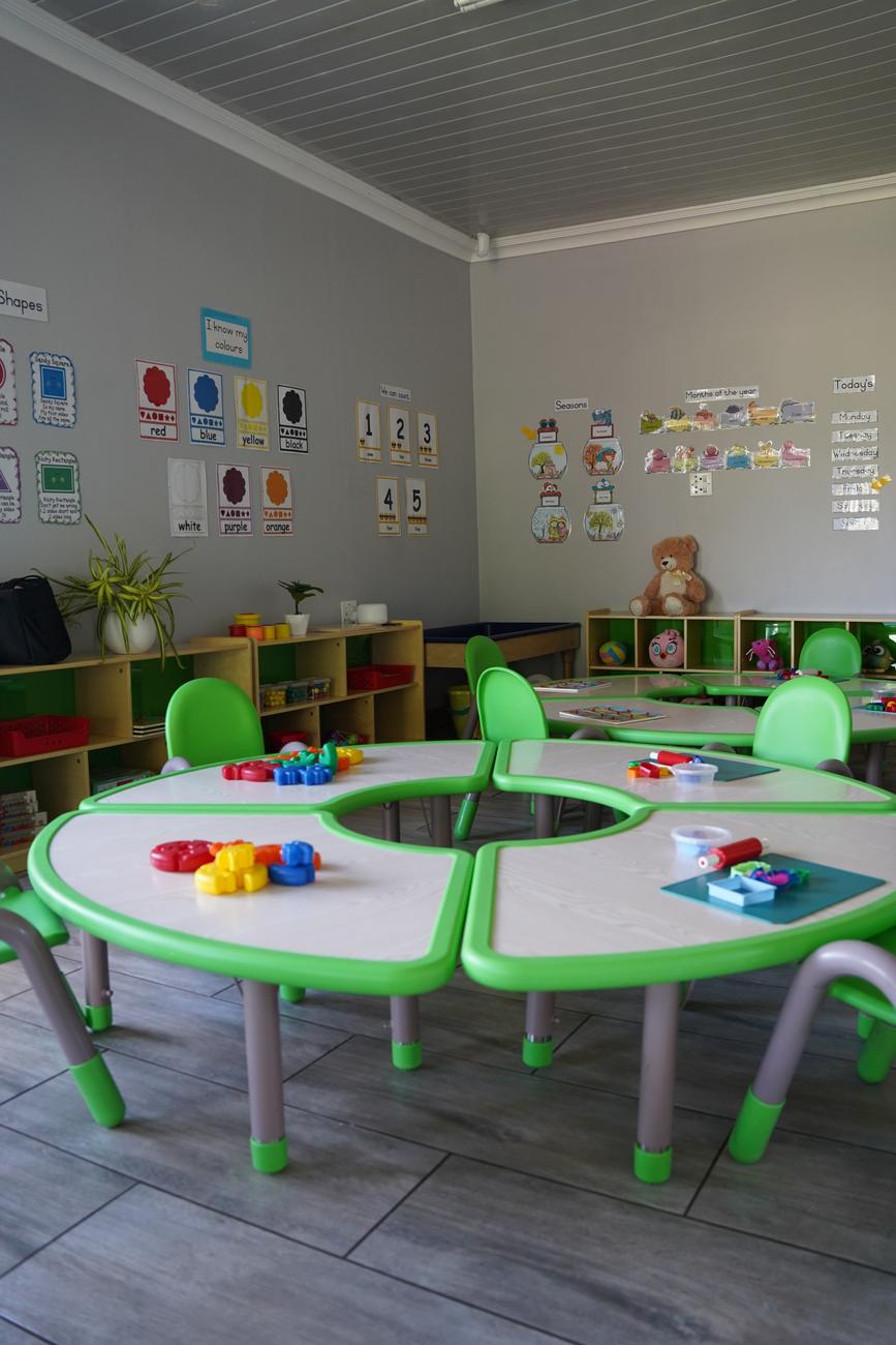 A Hibiscus classroom with round group tables and building toys on Rivier Street