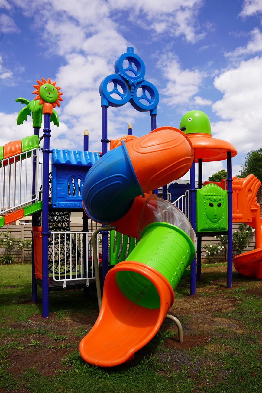 A jungle gym with a tube slide under a blue sky at the Hibiscus Rivier Street campus
